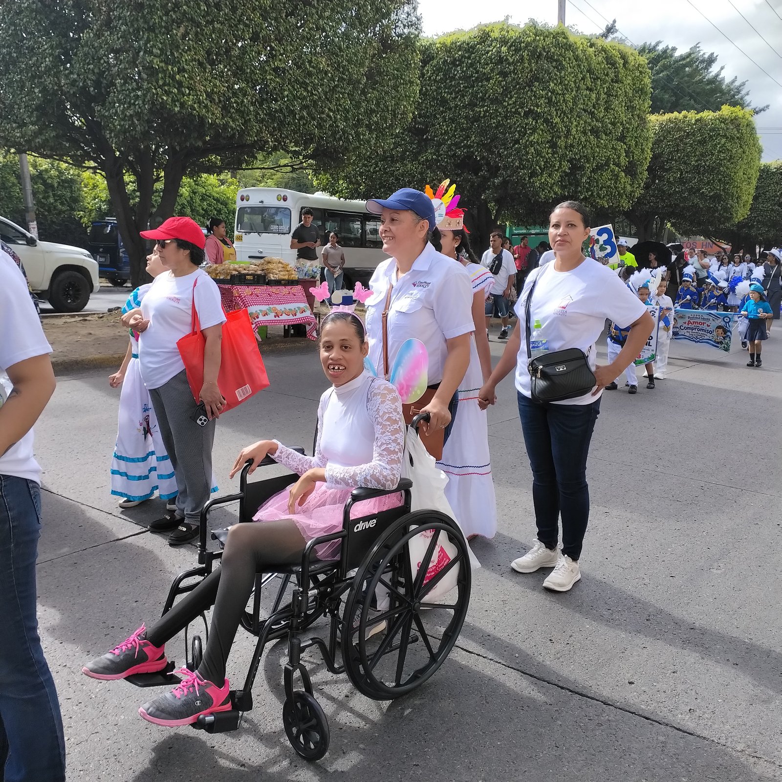 Banda marcial y niña en silla de ruedas participando en el desfile