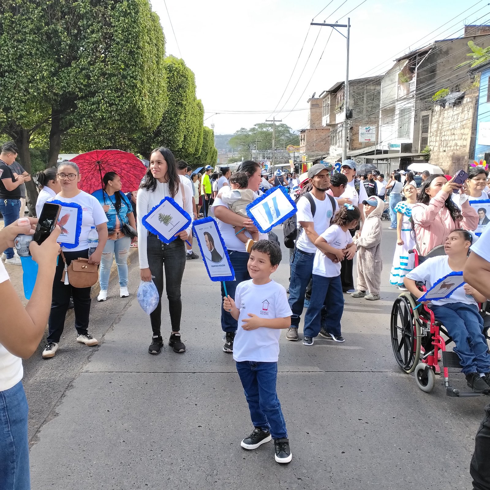 Niños portando símbolos patrios junto a compañero en silla de ruedas